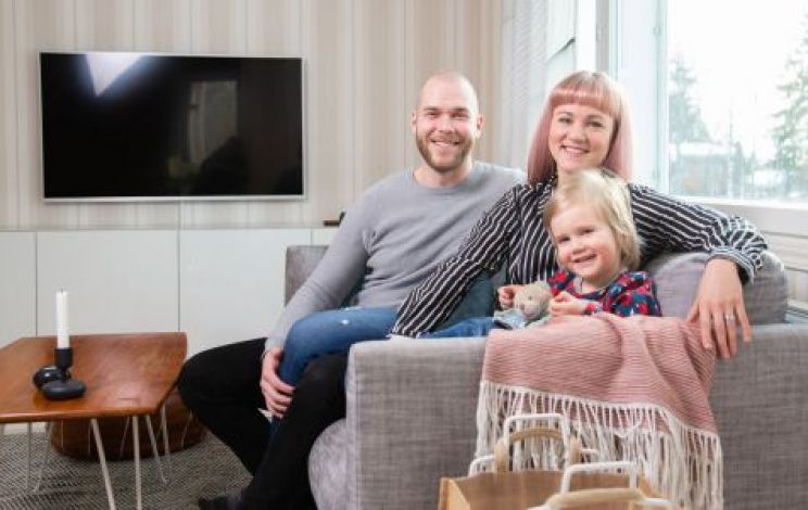 Miia ja Riku Jämsä tyttärensä kanssa sohvalla.